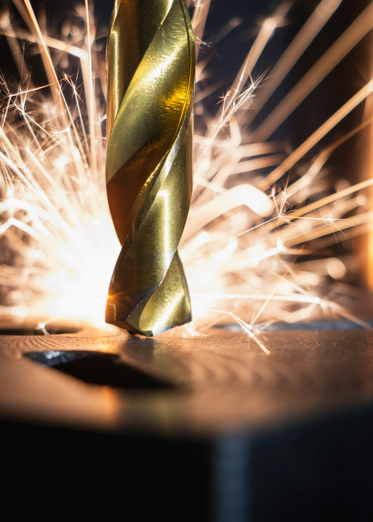 Close-up of a metal drill bit cutting through steel with sparks flying.